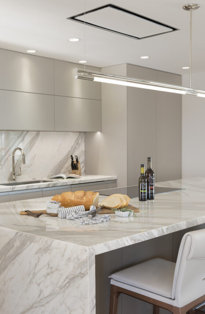 Luxury custom kitchen design with full spanning modern hanging light and custom wood cabinetry