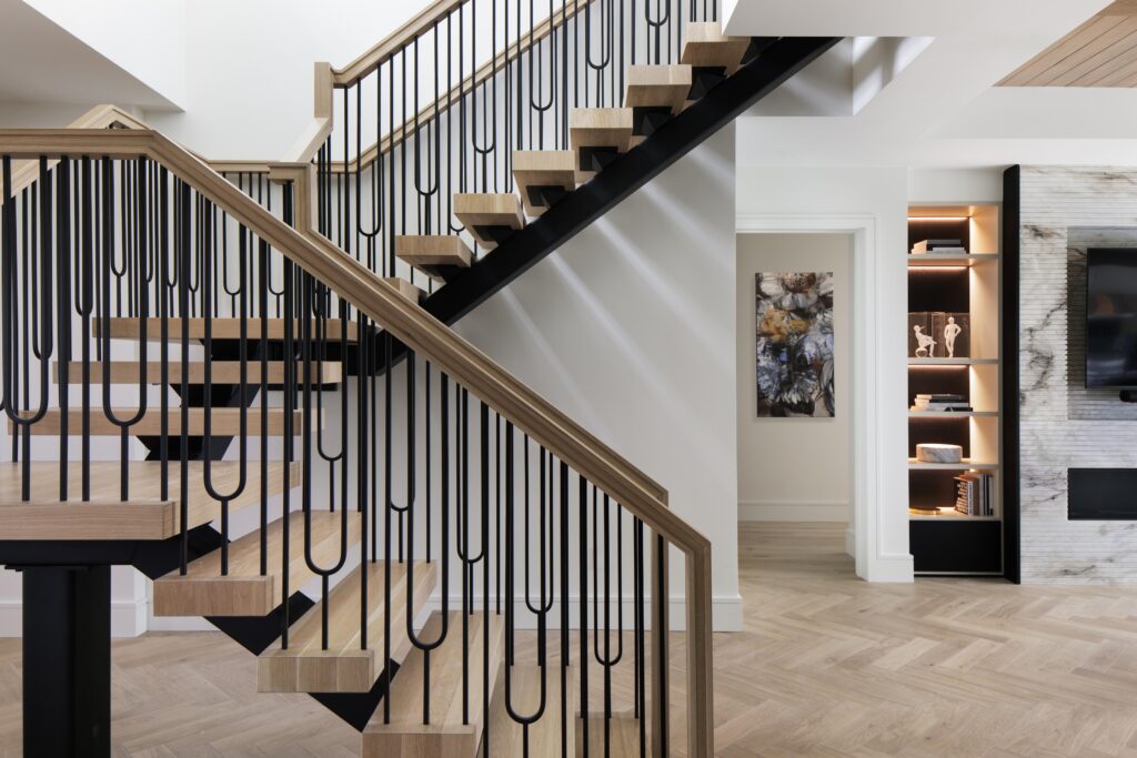 Custom designed staircase and flow into media room with complimentary contrasting features of black with natural wood and stone.