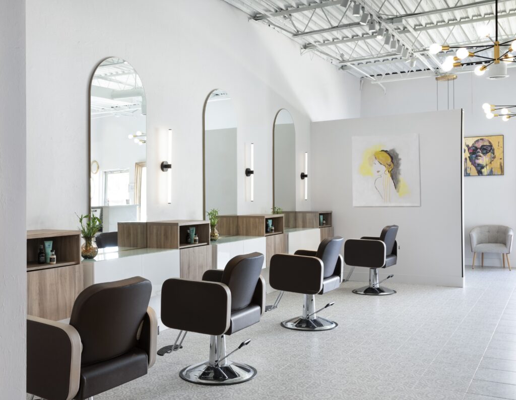 Commercial design of a luxury hair salon with individual stylist stations complete with custom cabinetry, mirrors, and sconces.