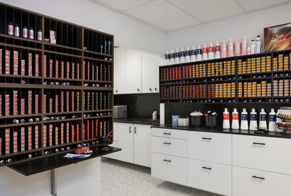 Custom cabinetry design in storage of commercial hair salon with custom sized shelving and drawers.