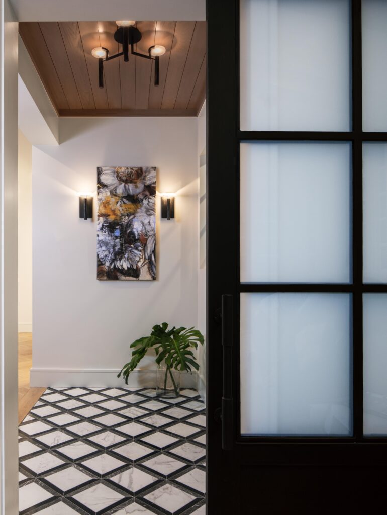 Hallway view with custom art and lighting, geometric tile flooring and natural wood ceiling detail by Florida designer Hudson Park Interior Design.