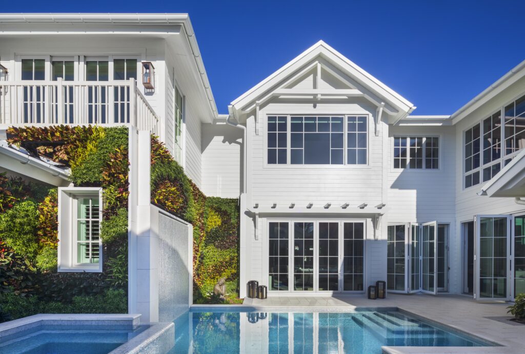 Modern coastal exterior home designed by Florida designer Hudson Park Interior Design, featuring pool, lanai, and balcony.