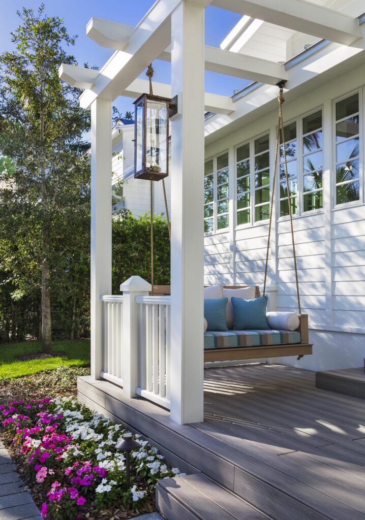 Exterior attached pergola on a modern coastal home, complete with cozy coastal design porch swing.