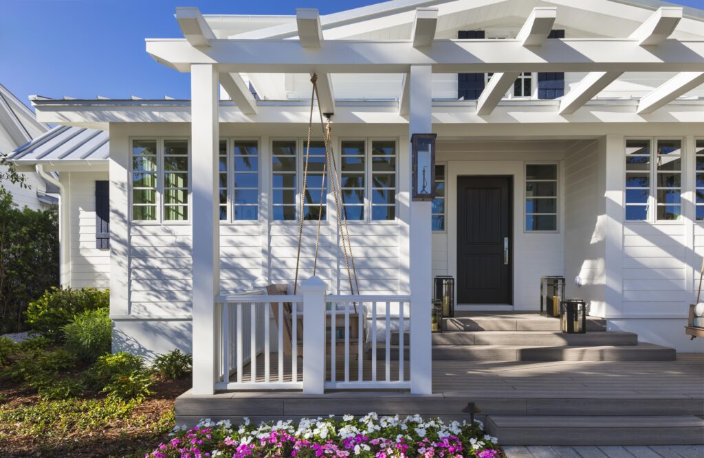 The exterior of a modern coastal home with cozy porch swing located in historic Old Naples, Florida.